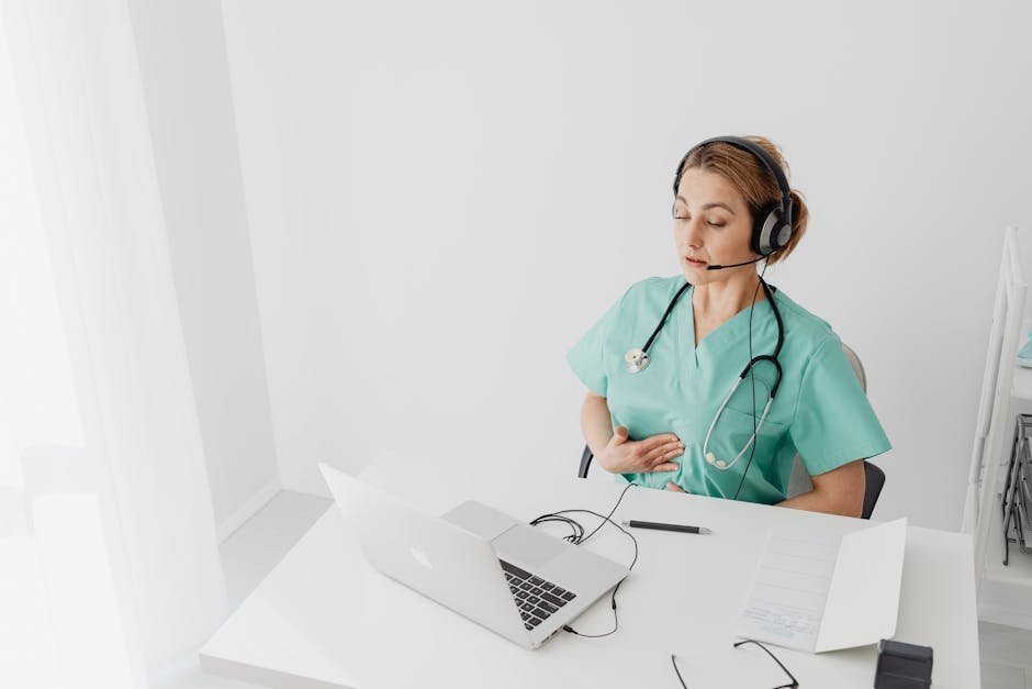 A clinician at a desk reviewing ASAM criteria assessment forms next to a laptop with a utilization review portal open