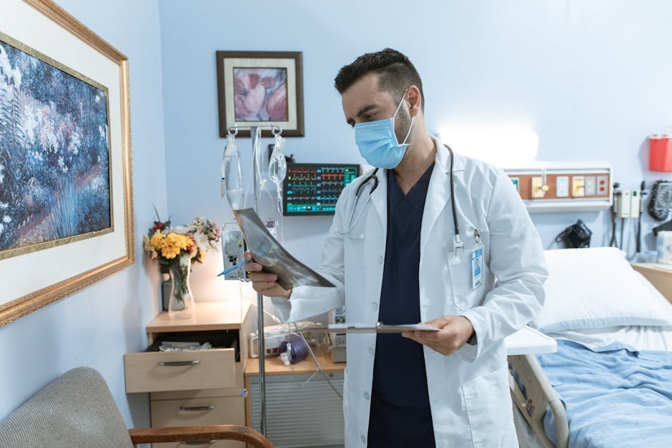 A patient sitting on a hospital bed talking with a clinician holding a tablet during a mental health intake assessment