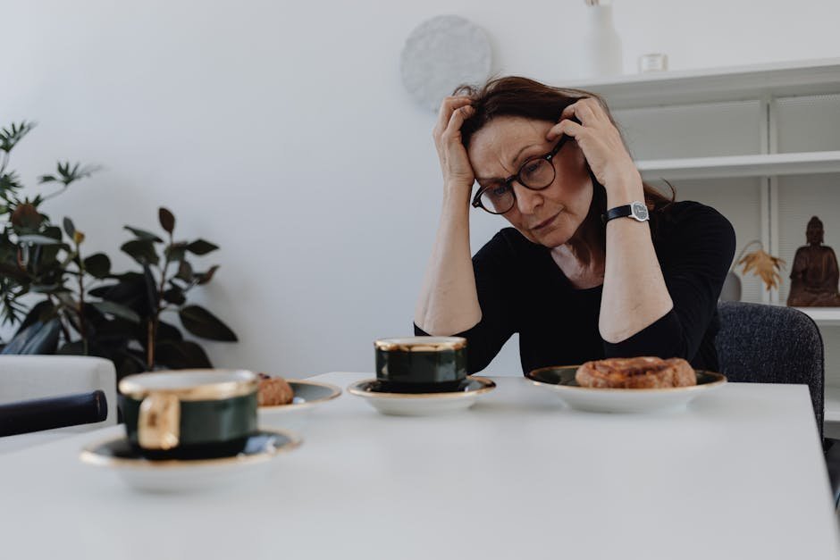 Person with depression sitting at a kitchen table looking at paperwork