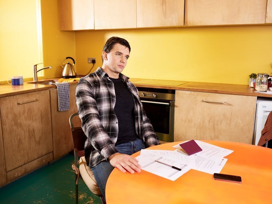 Person reviewing insurance paperwork at a kitchen table with laptop open, calm domestic setting, conveying the practical financial planning aspect of treatment