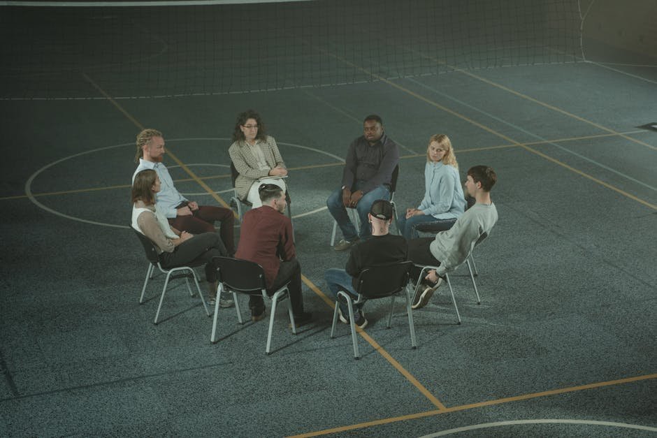 Group therapy session in a treatment center with patients seated in a circle and a therapist facilitating, conveying CBT-E group treatment setting