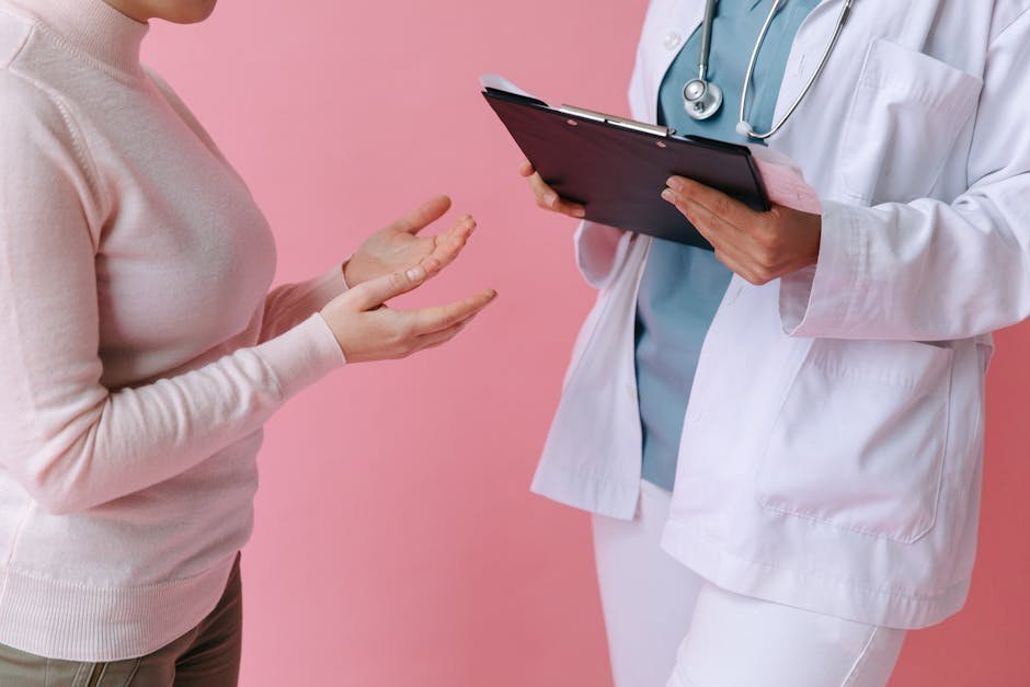 Acute psychotic break treatment follow-up: a doctor speaking gently with a young patient at a quiet outpatient appointment, the kind of warm clinical setting where recovery work continues after discharge