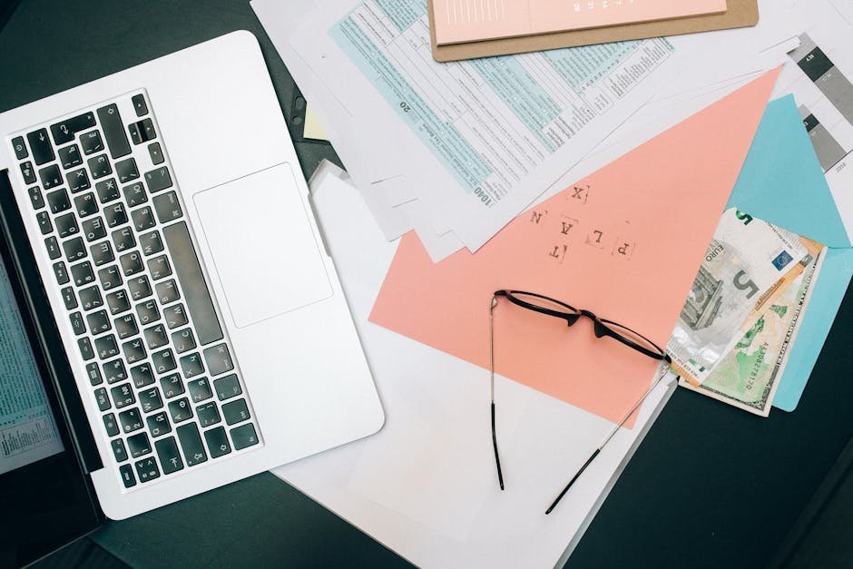 Open enrollment mental health comparison work: hands typing on a laptop next to a printed plan summary, the careful side by side review that protects therapy and psychiatry coverage for the year ahead